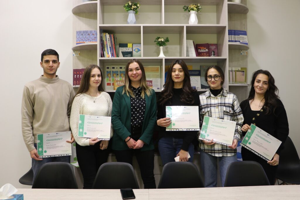 group of young participants standing with diploma in an office room