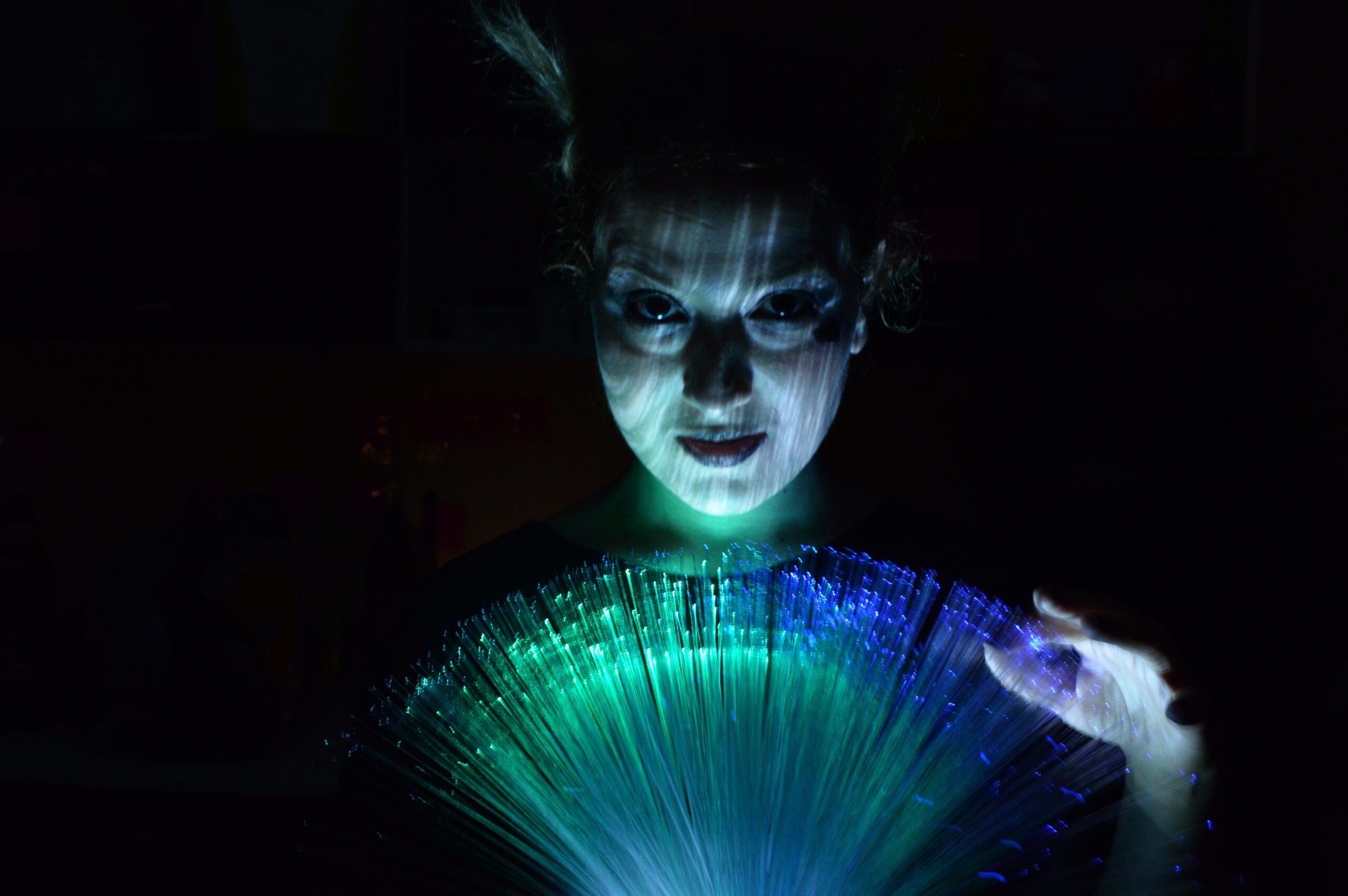 young girl in dark room with colourful light on her face