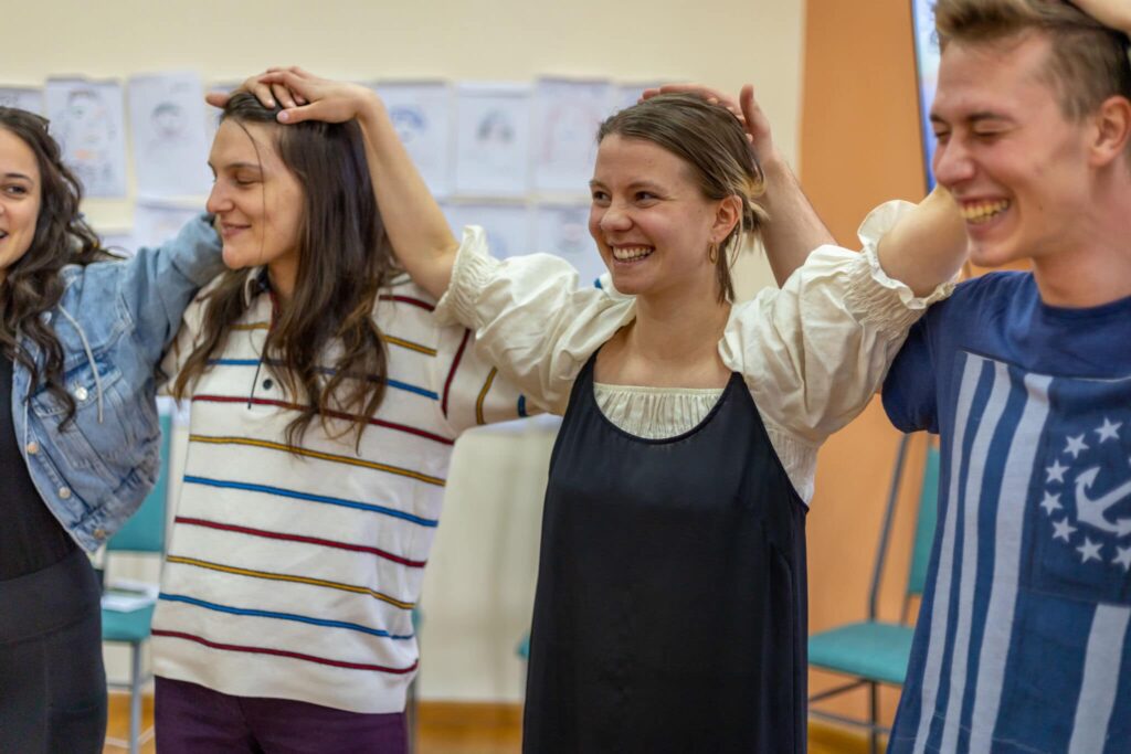 young people holding hands at their heads in a seminar room