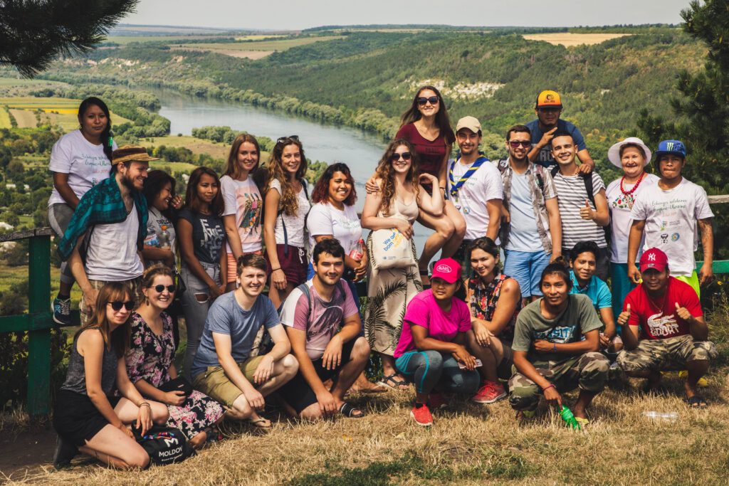 a group of youth from Ukraine and French Guyana in front of a green valley with a river