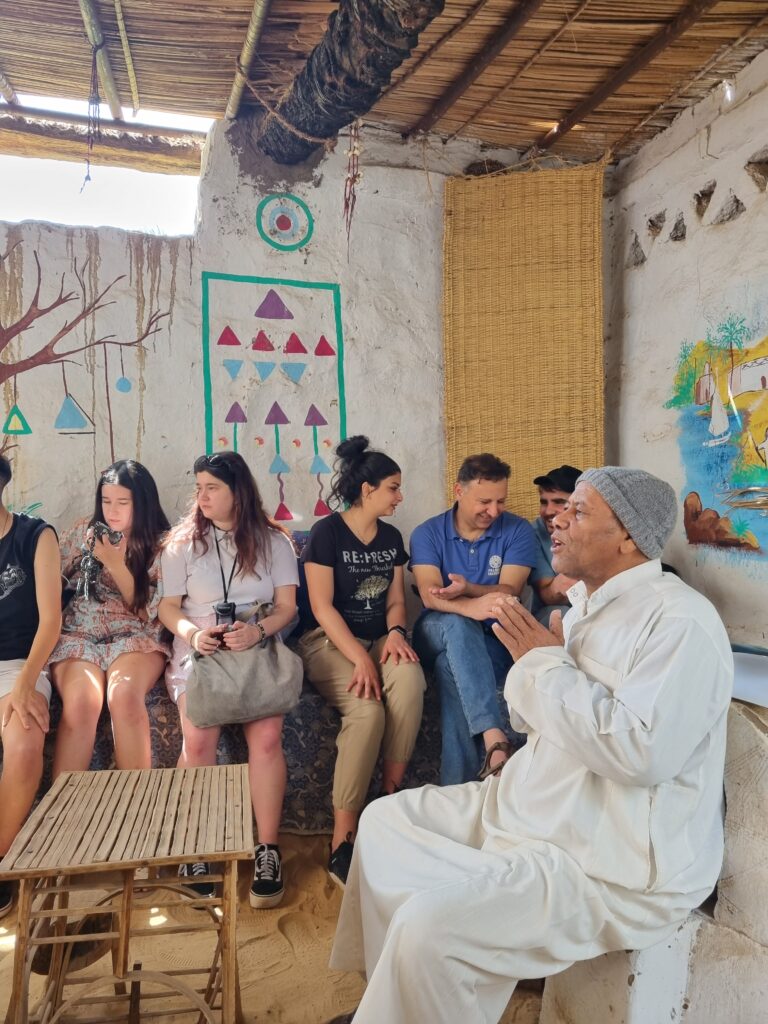 youth listening to a Nubian man, indoor, colourful drawings on the walls