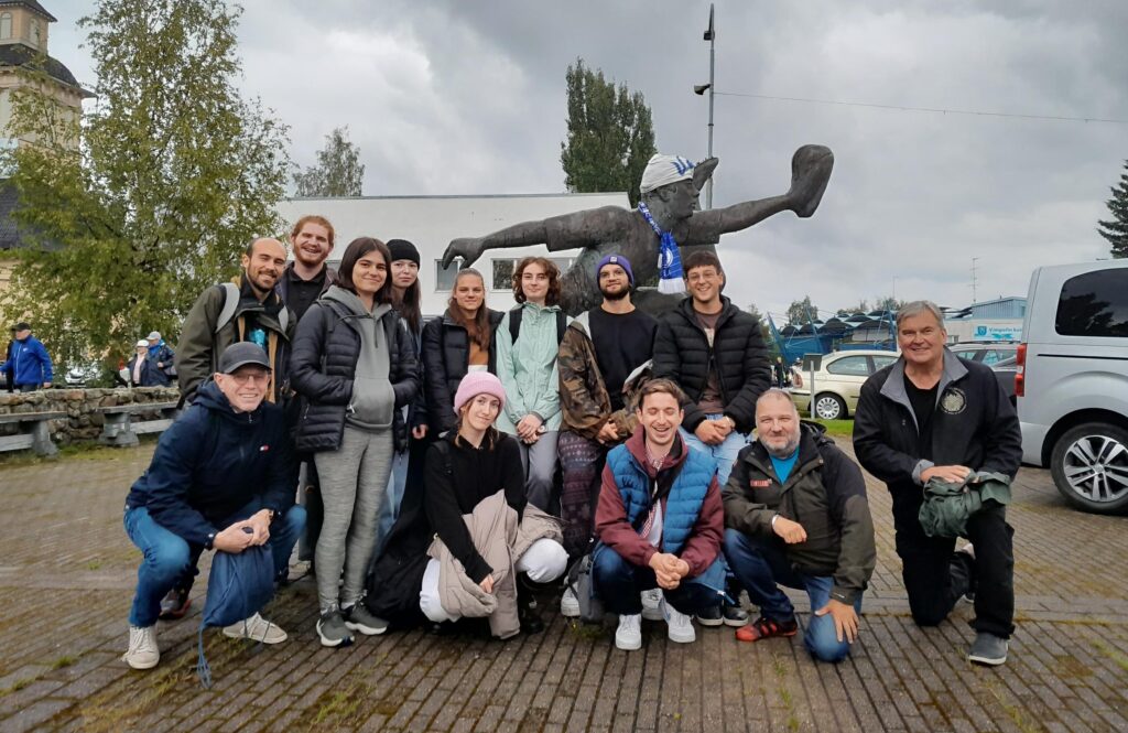 group of youth workers posing in front of a monument, cloudy sky