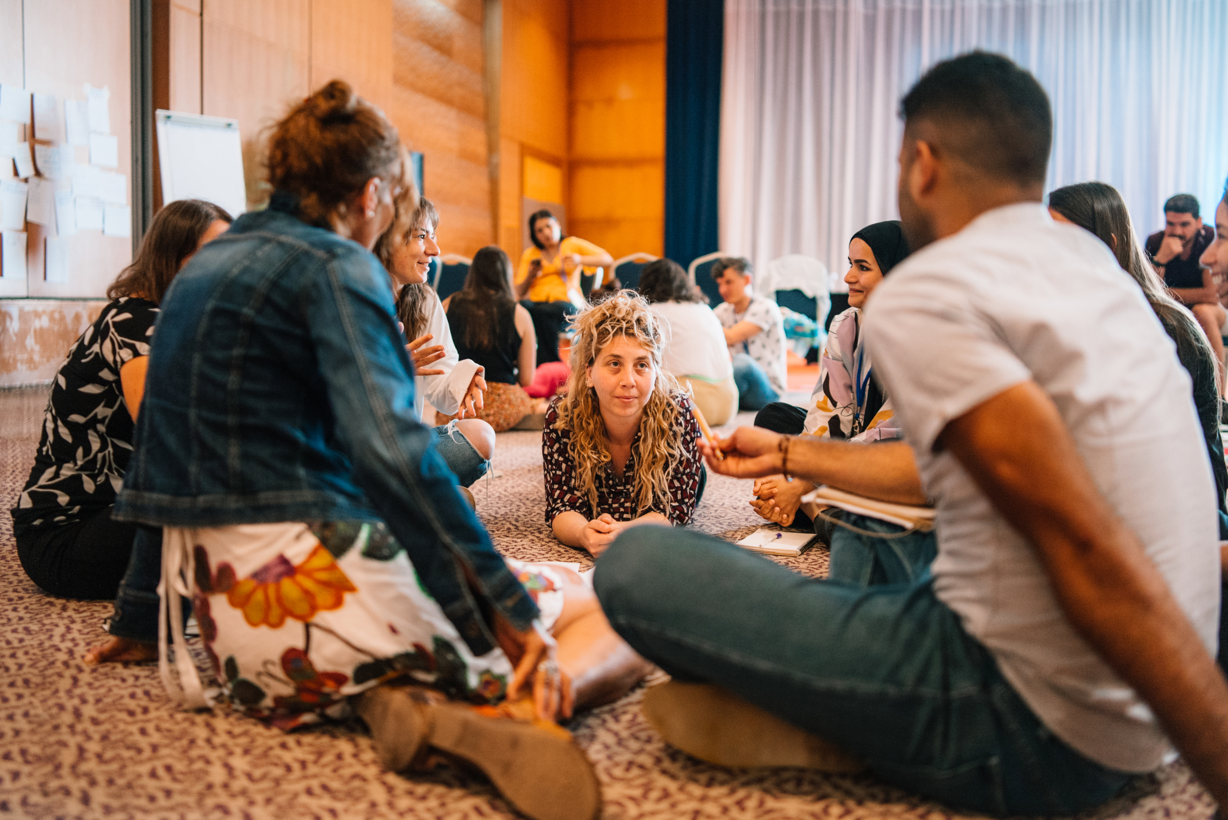 A group of young people sit on a floor and discuss