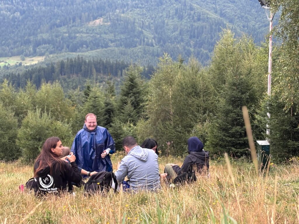 4 young people siting around with a view on green hills